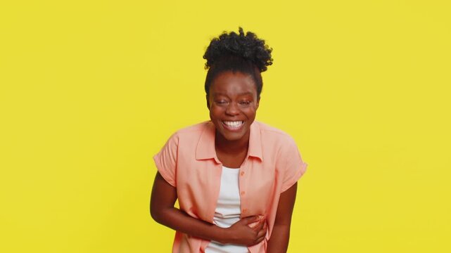 African American woman pointing finger to camera, laughing out loud, taunting making fun of ridiculous appearance, funny joke anecdote, bullying abuse. Black girl isolated on yellow background indoors