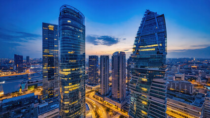 Obraz premium A vibrant cityscape at dusk, showcasing modern skyscrapers illuminated against the twilight sky