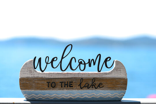 Decorative sign that says Welcome To The Lake on a shelf outside during the summer at Lake Couer D'Alene, Idaho. 