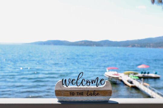 Decorative sign that says Welcome To The Lake on a shelf outside during the summer at Lake Couer D'Alene, Idaho. 