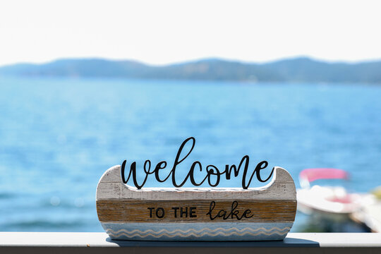 Decorative sign that says Welcome To The Lake on a shelf outside during the summer at Lake Couer D'Alene, Idaho. 