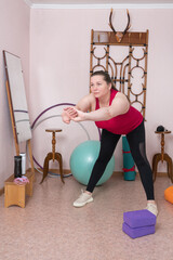 Middle aged woman is doing forward bend during fitness workout at home. Full length view of 44 year...