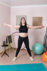 Full length of an fitness woman is executing five pointed star pose during morning fitness training at home. Woman is Caucasian, and is attired in sportswear, comprising black top, leggings, sneakers