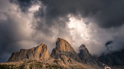 Jagged mountain peaks rise sharply under a dramatic sky filled with dense, swirling clouds, creating a moody and intense natural scene.