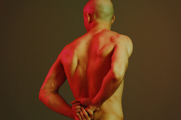 Strong man with an artistic pose stands against a patterned background, emphasizing the play of...