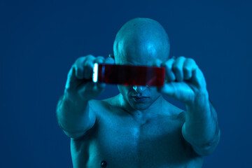 Strong man holding a red object in a dark blue atmosphere. The lighting creates an intriguing...