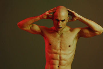 Athletic man flexing his muscles against a dark, moody background with dramatic lighting. The image...