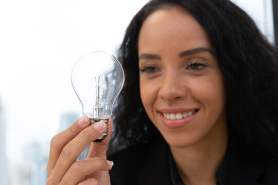 African american business woman with light bulb in modern meeting room. Multi-Ethnic Corporate Business Meeting. Female executive holding light bulb. Financial analysis.