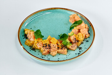 A Colorful Salmon Dish Featuring Citrus Segments, Black Salt, and Fresh Greens on a Turquoise Plate for a Gourmet Culinary Experience
