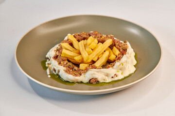 Delicious Dish Featuring Creamy Sauce, Juicy Minced Meat, Crispy French Fries, and Flavorful Herbs Presented in a Modern Round Plate
