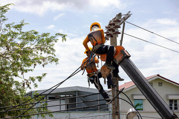 Two electric utility workers performing high-voltage maintenance on a power pole, fully equipped...