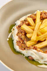 A Delicious Plates Featuring Savory Mix of Minced Meat Surrounded by a Ring of Creamy Sauce Accompanied by Crispy French Fries for a Tempting Delight