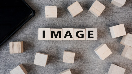 The word IMAGE created from wooden letter blocks on a concrete tabletop. Concept for visual media, photography, and digital content creation.
