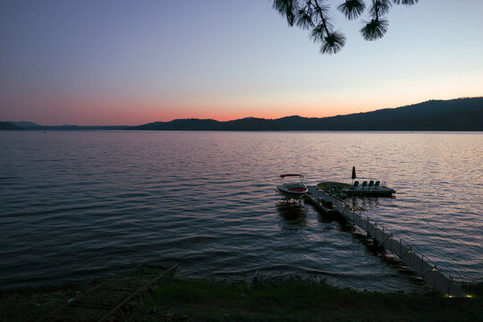 Warm sunset over lake Couer D'Alene in Idaho. Dusk brings a colorful hue in the sky over the pretty water. A boat dock is in the forefront.