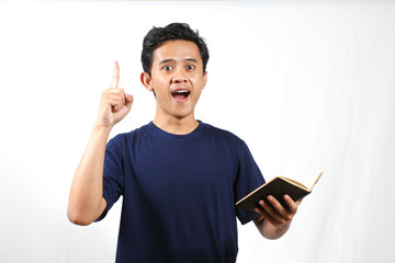 Excited young man holding open book and raising finger with bright idea