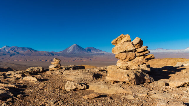 Apachetas in Chilean desert with panoramic view of Licancabur Volcano &ndash; Spiritual landscape and cultural symbolism&rdquo;