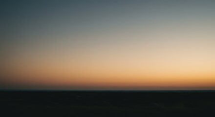 A serene sunset sky over a dark landscape