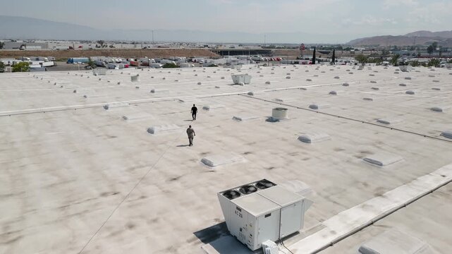 HVAC Technicians Pressure Washing Rooftop AC Units on Commercial Building