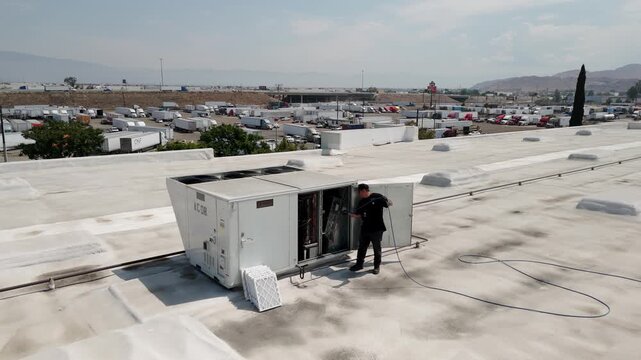 HVAC Technicians Pressure Washing Rooftop AC Units on Commercial Building