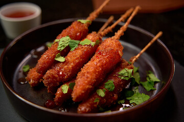 Crispy Coated Skewered Delicacies Served with Sauce and Fresh Herbs, A Delightful Treat for Food Lovers Looking for Flavorful Snacks and Appetizers