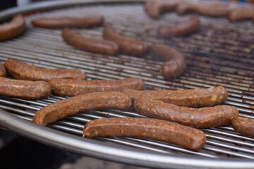 Photo. Process of cooking meat and chicken sausages on grill on metal grate over coals at harvest autumn festival, city holiday Tbilisoba, New Year street fair, Christmas market, fast food cafe. Eat