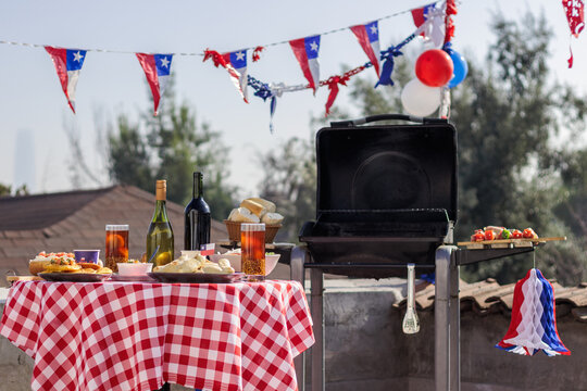Chilean Independence Day: Outdoor barbecue and traditional food setup with empanadas, completos, wine and patriotic decorations