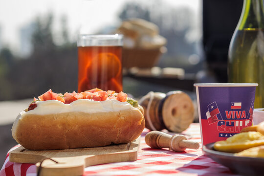 Chilean Independence Day: Traditional completos, mote con huesillo and wooden emboque toy on festive table