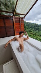 Handsome Man Relaxing on Holiday with Lush Green Valley and Misty Mountain Views in Chiang Mai, Thailand