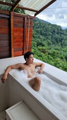 Handsome Man Relaxing on Holiday with Lush Green Valley and Misty Mountain Views in Chiang Mai, Thailand