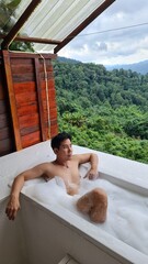Handsome Man Relaxing on Holiday with Lush Green Valley and Misty Mountain Views in Chiang Mai, Thailand