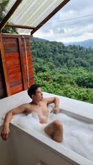 Handsome Man Relaxing on Holiday with Lush Green Valley and Misty Mountain Views in Chiang Mai, Thailand