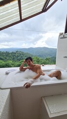 Handsome Man Relaxing on Holiday with Lush Green Valley and Misty Mountain Views in Chiang Mai, Thailand