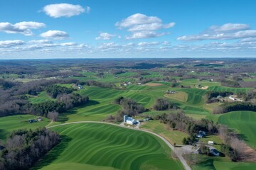 High-angle view of rolling farmland, rural homes, and a light-colored silo