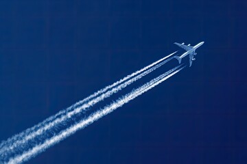 Airplane in flight, contrails against deep blue sky