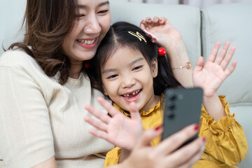 Mother and Daughter Video Call. Joyful moments shared while waving at family.