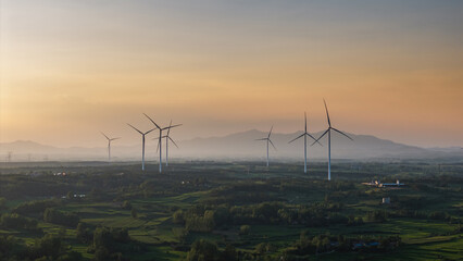 Wind turbines in a green field at sunset
