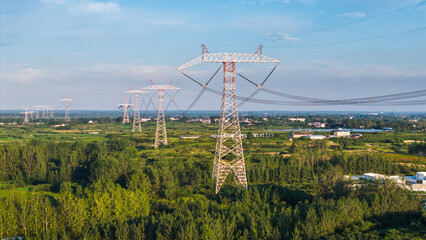 High-voltage transmission towers in the green field under the blue sky