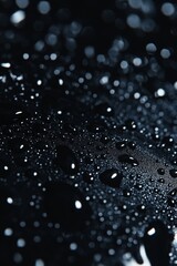 Sparkling droplets of rain on a dark surface.
