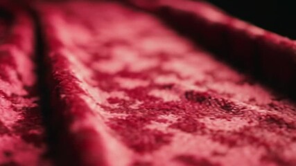 A close up view of rippled red velvet fabric with a soft and luxurious appearance in dim lighting - Powered by Adobe