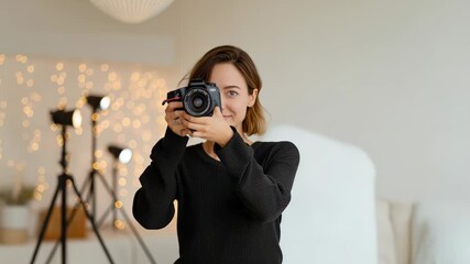 A confident female photographer holding a professional camera in a softly lit studio environment, photography, portraiture, or creative industries