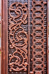 Part of ornate metal door featuring intricate carvings and detailed patterns, showcasing craftsmanship and artistic design elements, perfect for architectural and decorative themes