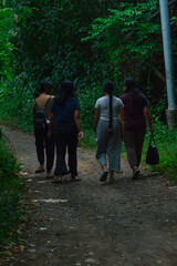 While walking side by side on a dirt path, the four girls engage in light conversation, immersed in...