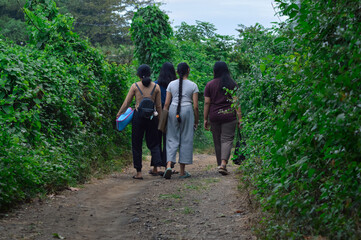 The girls enjoy a leisurely walk on a quiet forest path, surrounded by dense trees and fresh...