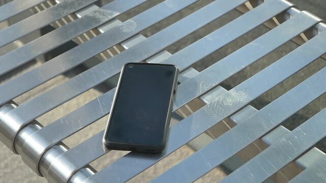 Smartphone left on metal table in public area, lost smart phone concept 