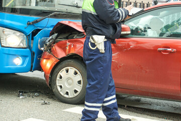 A police officer inspects a head-on collision between a bus and a car.
