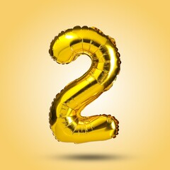 A shiny, golden number two balloon isolated on a bright yellow background. Ideal for birthday...