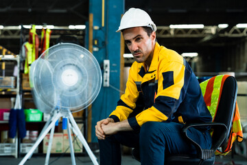 Caucasian male warehouse employee sitting on chair taking short break with serious facial...