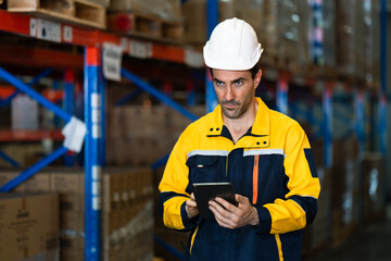 adult caucasian male warehouse staff using tablet to check stock level while walking through storage racks filled with cargo during logistic inspection process inside warehouse facility