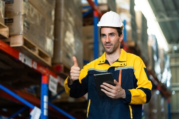 confident adult male warehouse manager smiling and giving thumbs up while holding digital tablet...