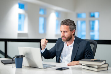 Obraz premium Business worker with laptop at office. Employee remote working in modern office. Business man on online meeting. Angry business man working online. Mature business man using laptop at workplace.